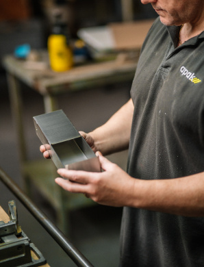 Een medewerker controleert een afgewerkt metalen onderdeel.