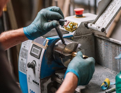 Een metalen onderdeel wordt ontbraamd op een draaibank.