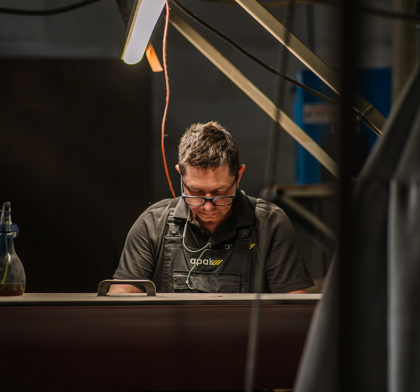 Een APAK-medewerker werkt aandachtig aan een metalen onderdeel in het atelier.